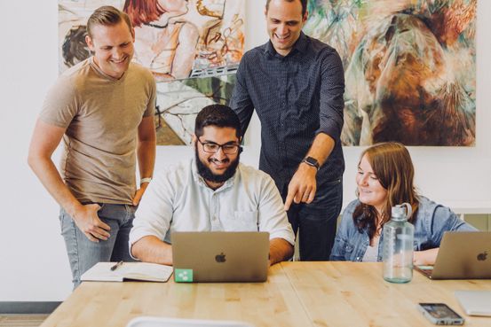 Grupo de jovenes sonriendo y usando computadoras