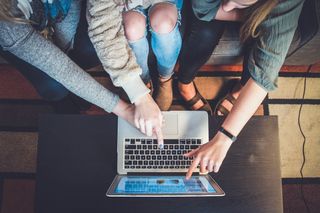 Personas apuntando a pantalla de laptop